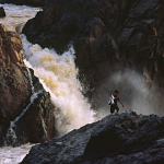 A Lao boy carries fish that he has harvested from a fish trap under the Li Phi Falls.
